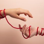 Human hands connected with red thread